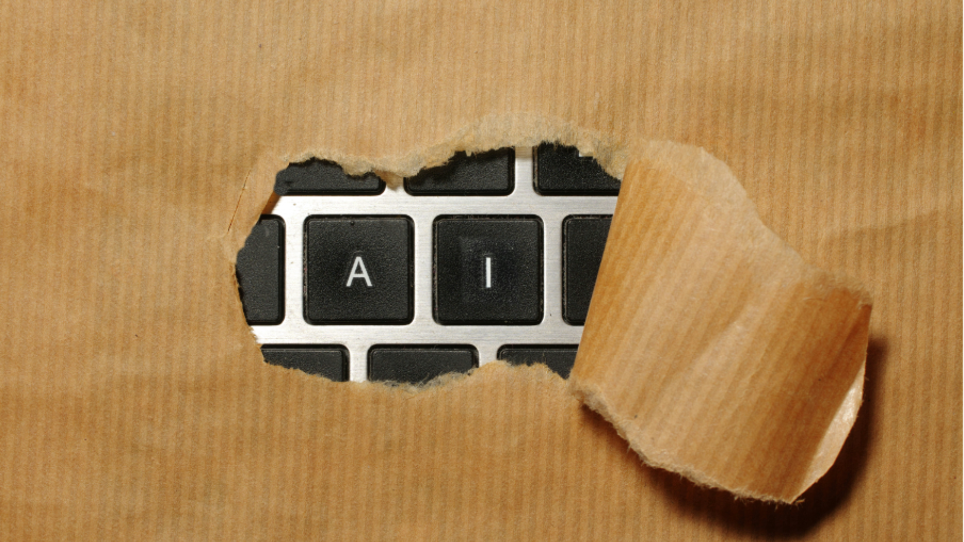 AI peeking out of ripped paper on a keyboard