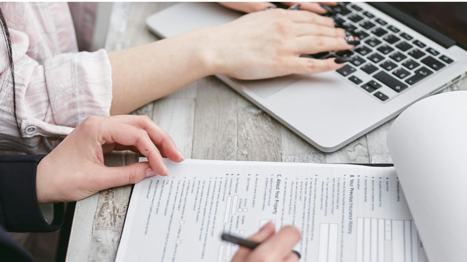 two people looking on a laptop and at insurance papers